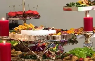 Exquisite fruit catering display featuring an assortment of fresh fruits like grapes, berries, and melon slices elegantly presented in gold trays.